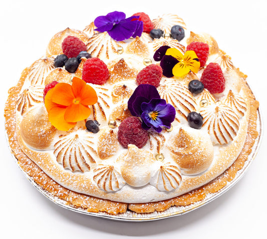 A handbaked meringue pie decorated with summer fruits and flowers