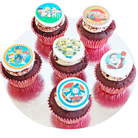 Selection of cupcakes for children, made from red velvet cake and topped with butter cream and an edible disc with a child-oriented image on it.