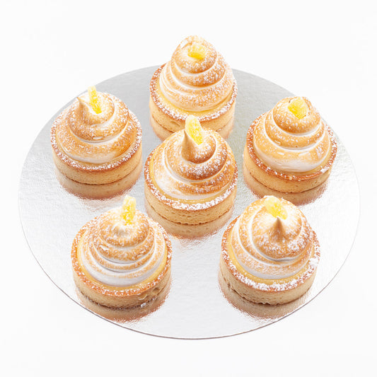 Six lemon meringue tartlets, topped with a generous meringue swirl and a piece of candied lemon.