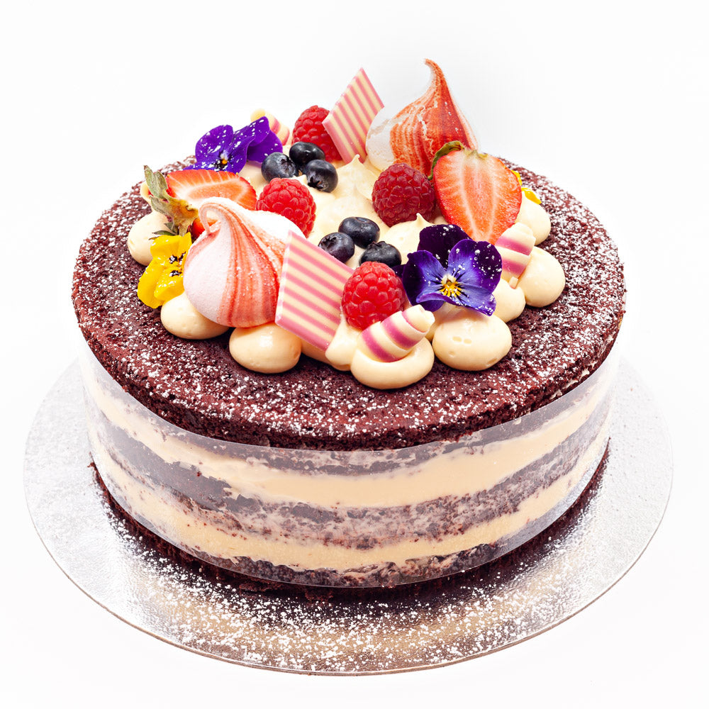 Three layers of red velvet cake, separated by two generous layers of butter cream. All topped with more butter cream and decorated with meringue swirls, chocolate curls, summer fruits and edible flowers.