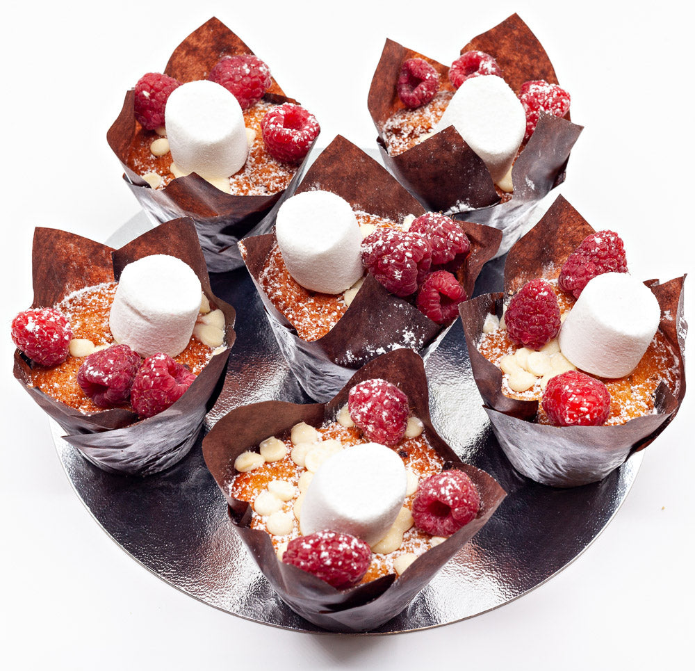 Six white chocolate and raspberry muffins with a marshmallow on top.